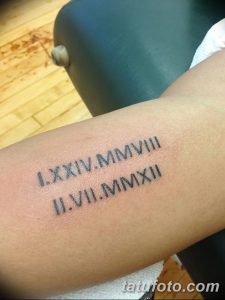 Фото тату на предплечье с римскими цифрами, выполненными черными чернилами. Две строки цифр, расположенные вертикально, создают стильный и лаконичный рисунок татуировки.