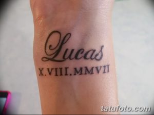 Фото тату: черное имя 'Lucas' и римские цифры 'X.VIII.MMVII' на запястье. Персонализированный и стильный рисунок татуировки.