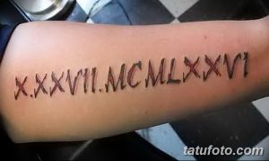 Фото тату: татуировка на предплечье, состоящая из римских цифр 'X.XXVII.MCMLXXVI', выполненная красными чернилами.