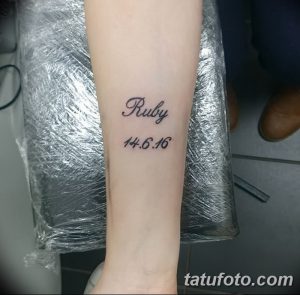 Фото тату: На предплечье выгравировано имя "Ruby" и дата рождения "14.6.16", выполненные изящным шрифтом.