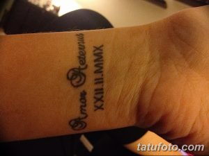 Фото тату на запястье с латинской фразой 'Amor Aeternus' и римскими цифрами XXII.II.MMX. Черно-белый рисунок, символизирующий вечную любовь.