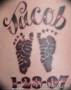 Фото тату с именем 'Jacob', отпечатками детских ног и датой '1-23-07', выполненное в черно-серых тонах на спине. Семейный рисунок татуировки.