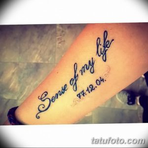Фото тату с надписью 'Sense of my life' и датой '77.12.04', выполненное синими чернилами на предплечье. Элегантный рисунок татуировки с каллиграфическим шрифтом.