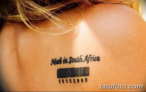 Фото тату с изображением штрих-кода и надписи 'Made in South Africa', выполненное черными чернилами на лопатке. Необычный рисунок татуировки с юмористическим подтекстом.