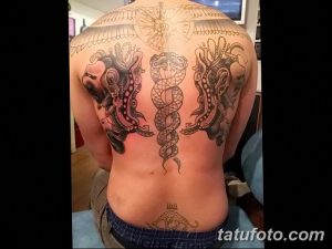 Фото масштабной татуировки Эскулапа с драконами на спине. Изображение выполнено в черном цвете и имеет сложный дизайн.