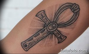 Фото тату на руке: стилизованный Анкх, выполненный с использованием точек и штрихов, создающих эффект объема и текстуры.