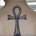 Фото татуировки Анкха, древнеегипетского символа жизни, выполненной в черно-серых тонах на спине человека.