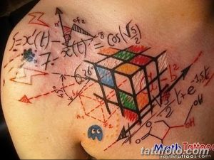 Фото тату: Яркая и необычная татуировка на плече, сочетающая математические формулы, кубик Рубика и абстрактные элементы. Цвета: красный, синий, зеленый.