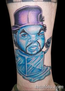 Фото тату с ярким портретом рэпера Ice Cube на предплечье. Мультяшный стиль, насыщенные цвета, детализированное изображение.