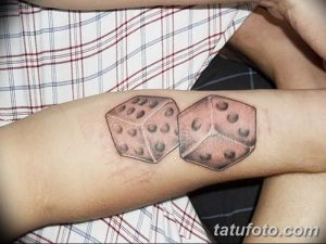 Фото реалистичной татуировки двух игральных костей на руке. Детализированное изображение с тенями и бликами.
