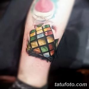 Фото небольшой татуировки кубика Рубика на руке, выполненной в реалистичном стиле. Яркие цвета и детализированная проработка.