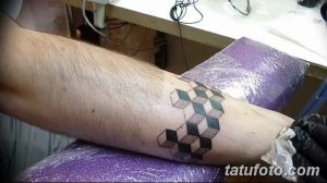 Фотография татуировки на предплечье, изображающей кубическую структуру. Татуировка выполнена в черно-белых тонах.