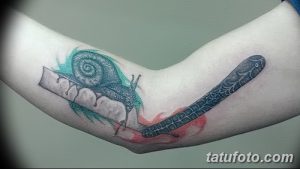 Фото тату на руке: бритва и улитка, выполненные в графическом стиле с элементами акварели. Оригинальный рисунок татуировки с красными брызгами.