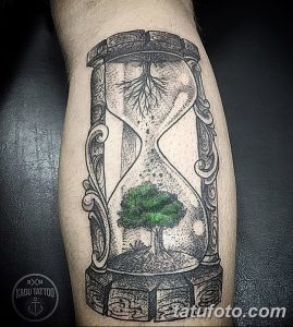 Фото тату на ноге с изображением песочных часов, в которых верхняя часть заполнена корнями дерева, а нижняя - зеленым деревом. Рисунок выполнен в стиле дотворк.