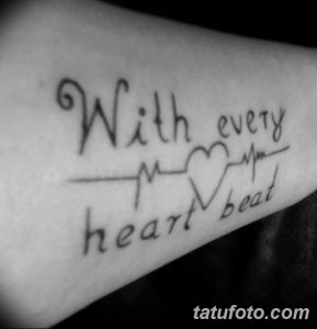 Фото татуировки на руке с надписью 'With every heart beat' и кардиограммой, образующей сердце. Черно-белый рисунок татуировки выглядит романтично и трогательно.