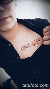 Фото тату кардиограммы на груди мужчины с добавлением даты '10.9.15'. Черный контурный рисунок татуировки выглядит минималистично и стильно.