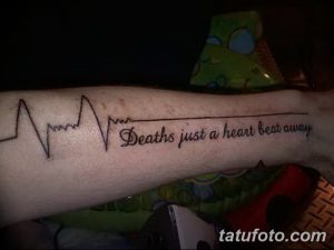 Фото тату на предплечье: линия сердцебиения, переходящая в фразу 'Death's just a heartbeat away'. Мрачный, но философский рисунок татуировки.