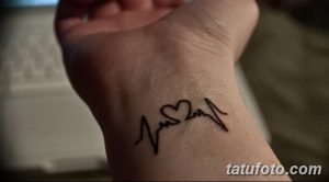 Фото тату: маленькая черная татуировка в виде сердцебиения с сердечком посередине, расположенная на запястье.