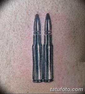 Фото минималистичной татуировки с изображением двух патронов, расположенных вертикально. Простой, но выразительный рисунок.