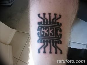 Фото тату на предплечье: черная татуировка с инициалами 'G33K' и стилизованной короной, выполненная четкими линиями.