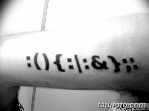 Фото тату с изображением смайлика, выполненного в стиле ASCII-art. Оригинальный и минималистичный рисунок татуировки.