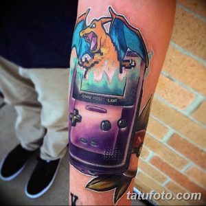 Фото тату с изображением портативной консоли Game Boy и покемона Charizard. Красочный и детализированный рисунок татуировки.