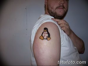 Фото тату с изображением пингвина Tux, талисмана Linux, на плече. Яркий и милый рисунок татуировки.