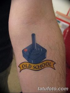 Фото тату: татуировка в стиле "Old School" с изображением джойстика и надписью "Old School" на предплечье. Яркий и ностальгический рисунок.