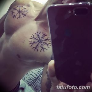 Фото тату: три небольшие рунические татуировки на груди, выполненные в минималистичном стиле тонкими черными линиями. Символичный и элегантный дизайн.