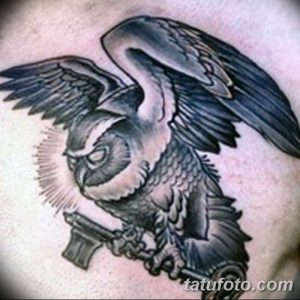 Фото тату совы с ключом в стиле blackwork на спине. Крупный рисунок, выполненный полностью в черном цвете с использованием плотных штрихов и геометрических форм.