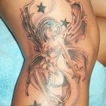 Фото тату феи с крыльями и звездами на плече. Детализированный рисунок с использованием ярких цветов и плавных линий.