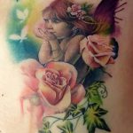 Фото тату феи с розовыми розами и голубями на лопатке. Реалистичный рисунок с использованием ярких и насыщенных цветов.