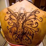 Фото тату феи с расправленными крыльями на спине. Черно-белый рисунок татуировки с детализированными узорами.