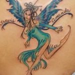 Фото тату феи на спине с луком и стрелами, с надписями имен 'Travis' и 'Amanda'. Детализированный рисунок татуировки, символизирующий защиту и любовь.