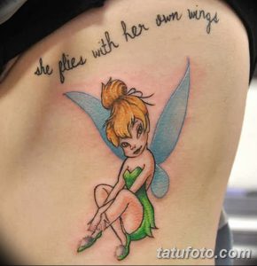 Фото тату феи на плече с надписью 'she flies with her own wings'. Детализированный рисунок татуировки в пастельных тонах.
