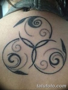 Фото тату трискеля на спине. Черно-белый кельтский узор с завитками и спиралями, символизирующий вечность и триединство.
