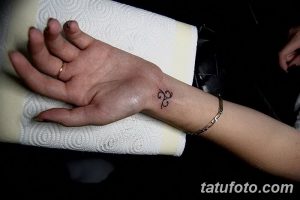 Фото тату на запястье: простой кельтский трилистник, выполненный черными линиями. Небольшой рисунок татуировки для девушек.