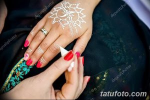 Фото менди: сложный узор хной на тыльной стороне женской руки, процесс нанесения.