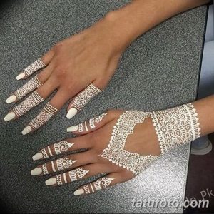 Фотография женских рук, украшенных сложными узорами хной. Рисунки покрывают ладони, пальцы и запястья, создавая эффект временной татуировки.