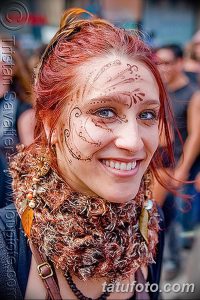 Фото тату на лице: золотые узоры и украшения, украшающие лоб и щеки. Традиционный восточный образ и яркий макияж.