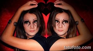 Фото тату мехенди на лицах двух девушек, создающих зеркальное отражение. Узоры выполнены хной черного цвета, подчеркивая мистическую атмосферу.
