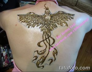 Фото рисунка хной феникса на спине, выполненного в коричневых тонах с использованием сложных узоров и детализированных перьев.
