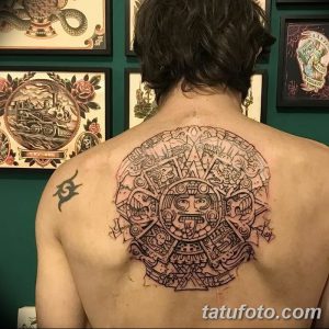 Фото тату: масштабный рисунок календаря майя на спине, выполненный в технике blackwork с четкими линиями и детальной проработкой символов.
