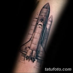 Фото тату: детализированная и реалистичная татуировка космического шаттла, выполненная в черно-серых тонах на руке.