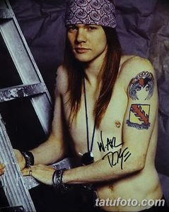 Фотография Слэша, гитариста Guns N' Roses, с татуировками на руке и банданой на голове.