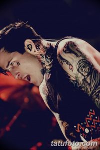 Фотография Post Malone с многочисленными татуировками на лице, шее и руках, демонстрирующими рисунки в стиле олд скул, надписи и другие детали.