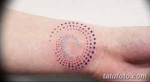 Фото татуировки на запястье: спираль, состоящая из разноцветных точек. Яркий и необычный дизайн, минималистичный стиль.