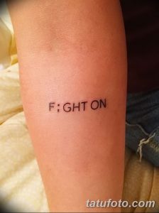 Фото тату надписи 'FIGHT ON' черным цветом, выполненной на предплечье. Минималистичный рисунок татуировки, вдохновляющий на борьбу и преодоление трудностей.