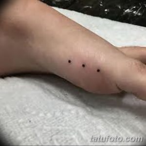 Фото тату на стопе: три небольшие черные точки, расположенные в ряд. Минималистичный рисунок татуировки, символизирующий надежду, веру и любовь.
