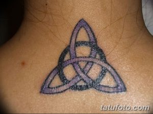 Фото тату кельтского трилистника в фиолетовых тонах, расположенного на шее у девушки. Татуировка выполнена в мягком стиле с использованием плавных переходов.